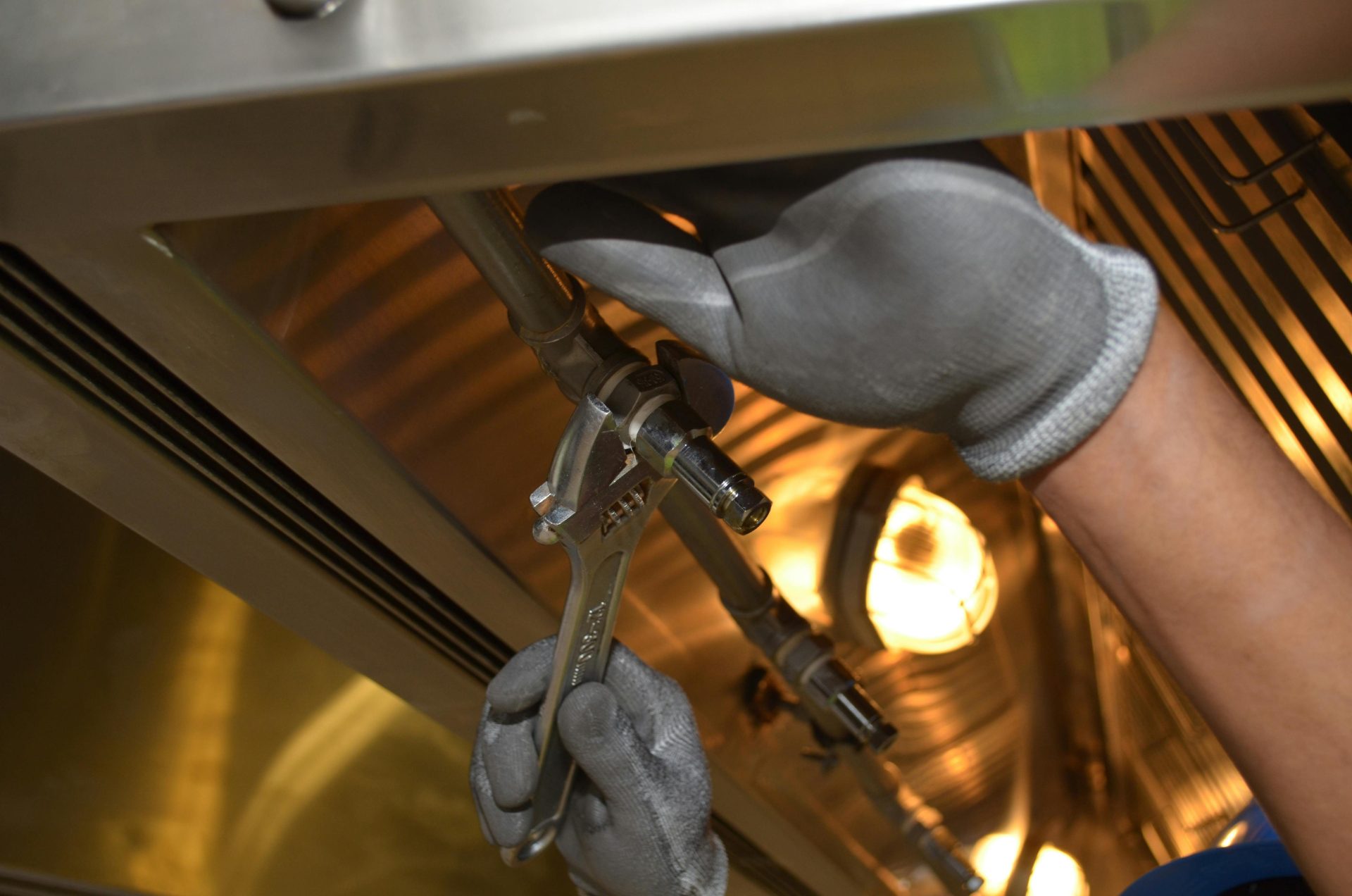 Ein Arbeiter repariert mit Werkzeugen Rohre in einer industriellen Innenumgebung.